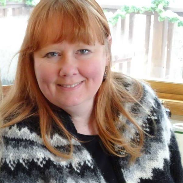Headshot of red-headed woman in a black and grey sweater
